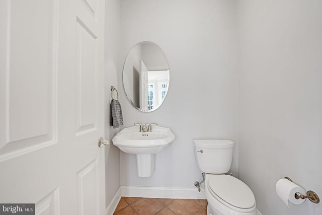 half bath with tile patterned floors, toilet, and baseboards