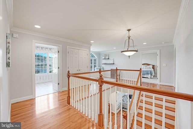 corridor with an upstairs landing, light wood finished floors, and crown molding