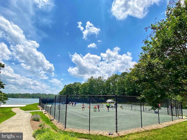 view of sport court featuring a water view and fence