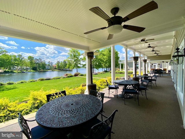 view of patio with outdoor dining space, a water view, and ceiling fan