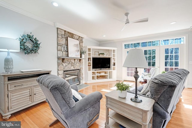 living room with a fireplace, light wood-type flooring, and ornamental molding