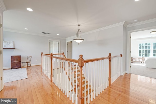 hallway with baseboards, recessed lighting, light wood-style floors, crown molding, and an upstairs landing