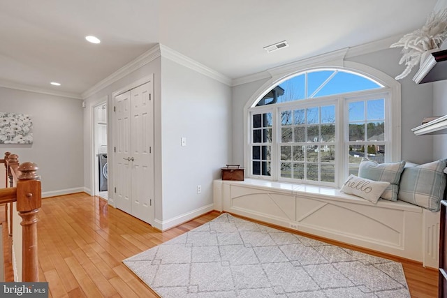 foyer featuring baseboards, light wood-style floors, visible vents, and ornamental molding