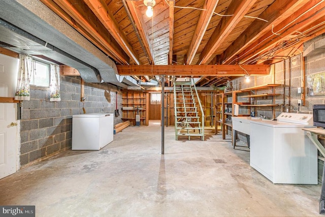 basement with concrete block wall, stairway, washing machine and clothes dryer, refrigerator, and a sink