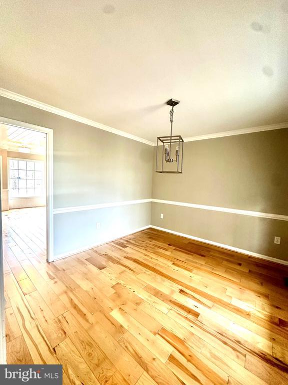 unfurnished room featuring hardwood / wood-style floors, baseboards, and ornamental molding