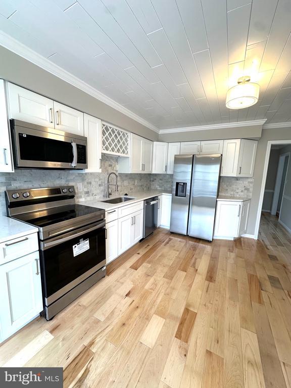 kitchen featuring a sink, white cabinets, appliances with stainless steel finishes, and light countertops