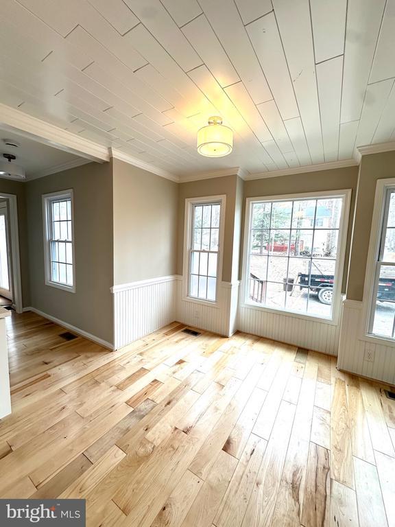 interior space with light wood finished floors, ornamental molding, and wainscoting