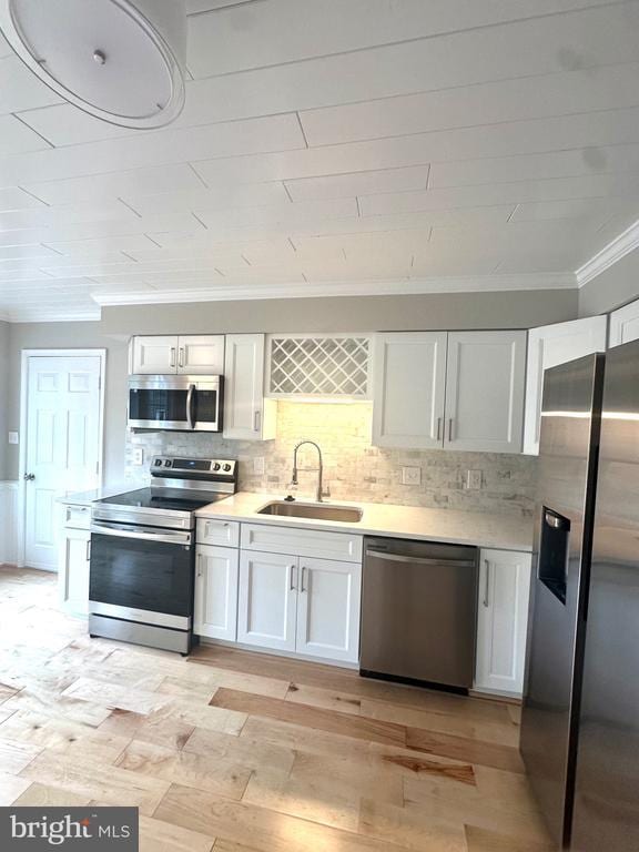 kitchen featuring ornamental molding, a sink, white cabinets, and appliances with stainless steel finishes