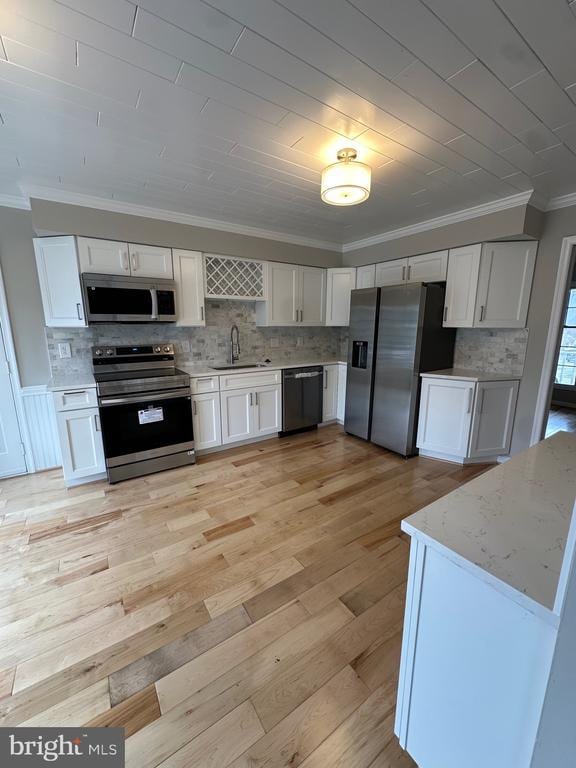 kitchen with crown molding, a sink, appliances with stainless steel finishes, and white cabinetry