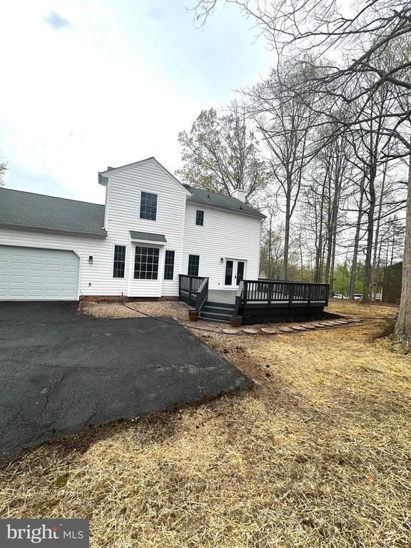 back of property featuring a garage, aphalt driveway, and a deck