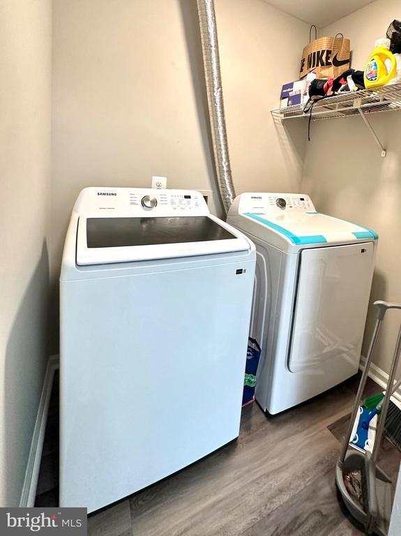 clothes washing area with washing machine and dryer and dark hardwood / wood-style floors