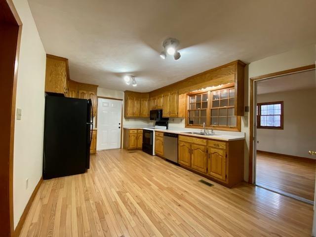 kitchen featuring sink, light wood-type flooring, and black appliances