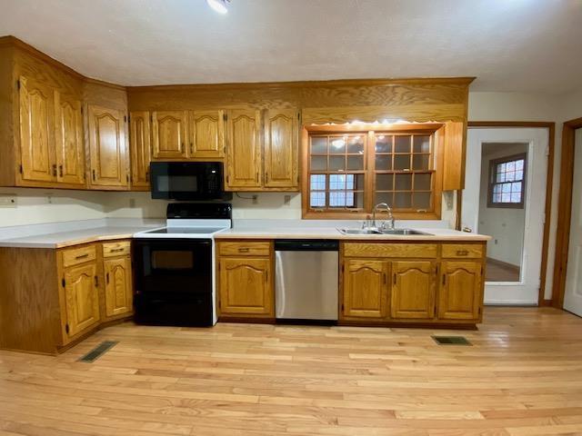 kitchen featuring sink, range with electric stovetop, stainless steel dishwasher, and light wood-type flooring