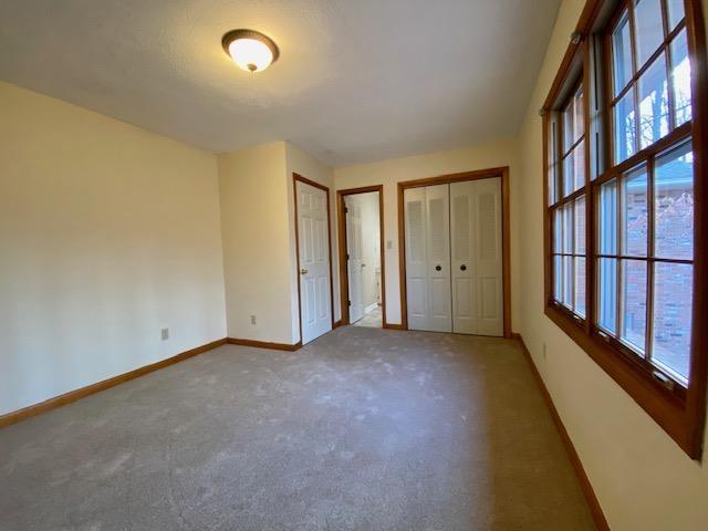 unfurnished bedroom featuring carpet and two closets