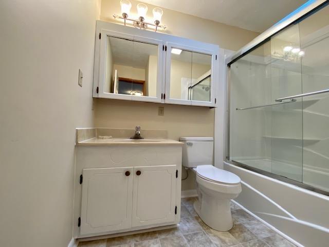 full bathroom featuring enclosed tub / shower combo, vanity, and toilet