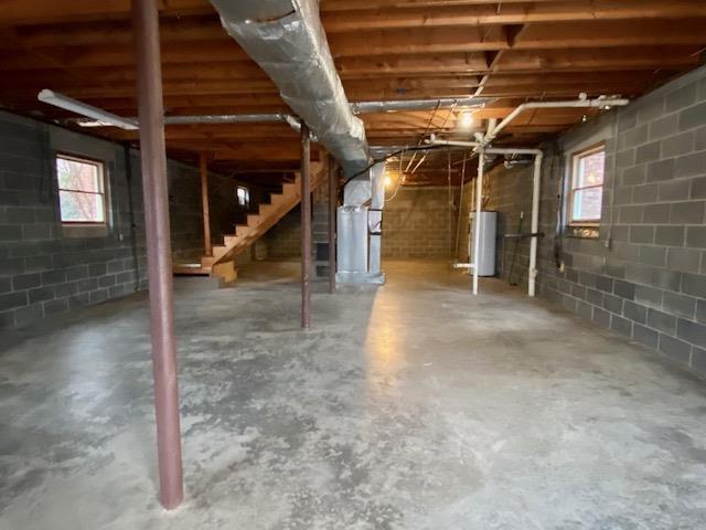 basement with water heater and a healthy amount of sunlight