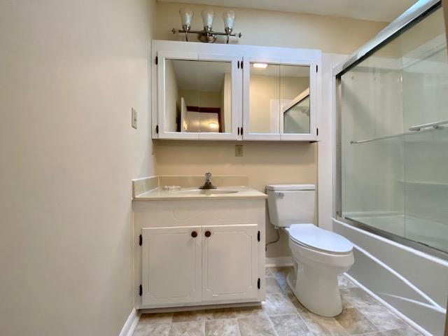 full bathroom featuring vanity, enclosed tub / shower combo, and toilet