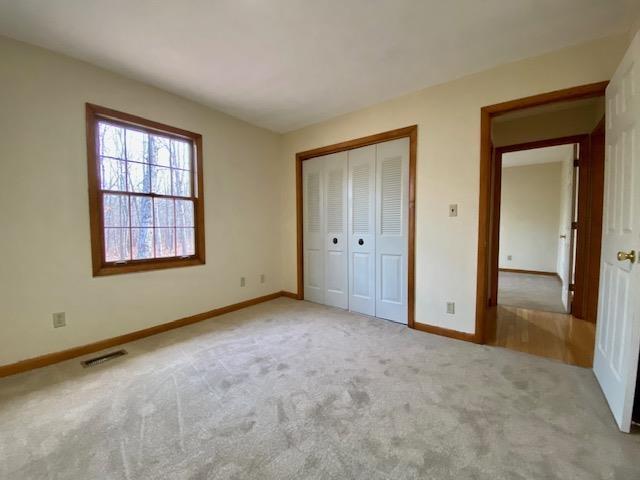 unfurnished bedroom featuring light carpet and a closet