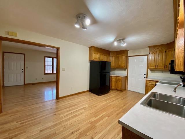 kitchen with sink, light hardwood / wood-style floors, and black appliances