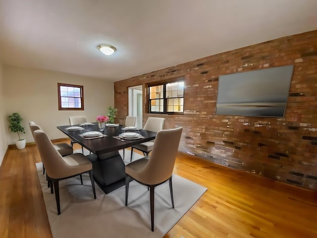 dining space featuring brick wall and light hardwood / wood-style flooring