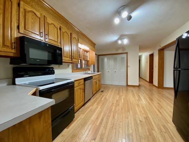 kitchen with sink, light hardwood / wood-style flooring, and black appliances