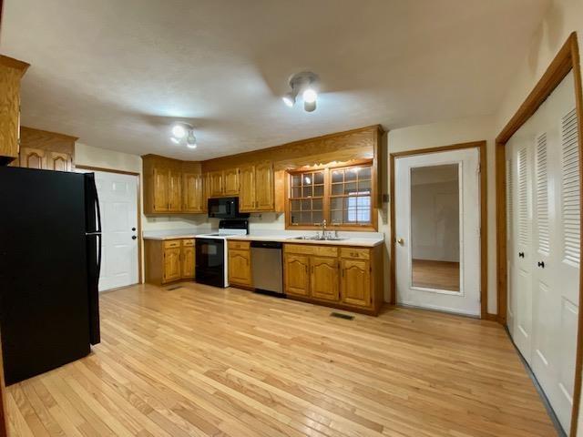 kitchen featuring sink, light wood-type flooring, and black appliances