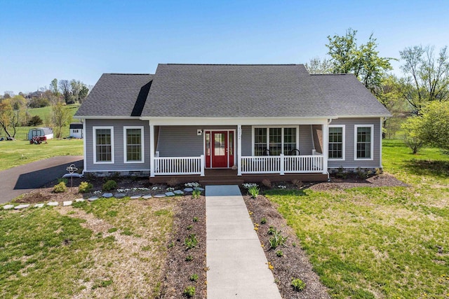 view of front facade with covered porch, a front yard, and roof with shingles