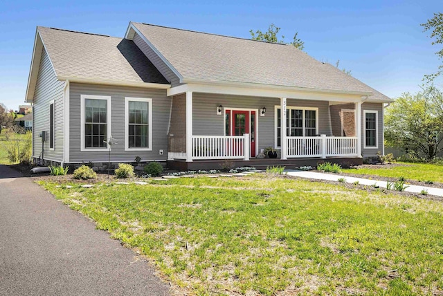 view of front facade with a porch, roof with shingles, and a front yard