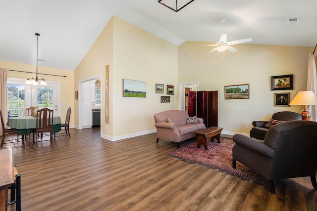 living room featuring dark wood finished floors, visible vents, baseboards, high vaulted ceiling, and ceiling fan with notable chandelier