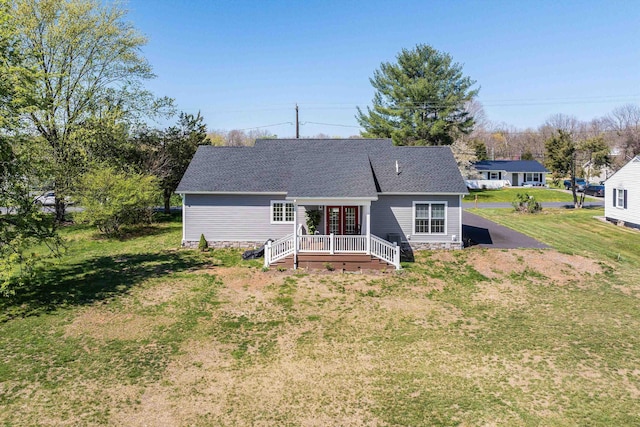 rear view of house with a wooden deck, a shingled roof, and a yard