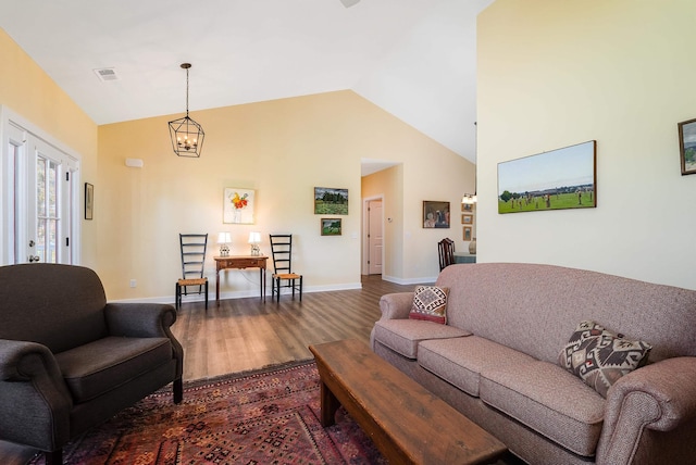 living area with wood finished floors, visible vents, baseboards, a chandelier, and high vaulted ceiling