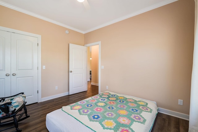 bedroom featuring baseboards, crown molding, dark wood-style floors, and a closet
