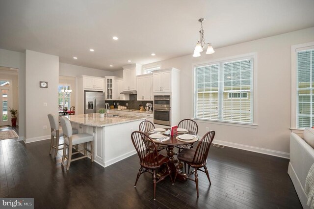 dining room featuring sink, a notable chandelier, and dark hardwood / wood-style flooring