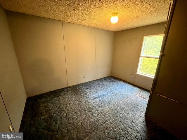 empty room featuring visible vents, carpet flooring, and a textured ceiling