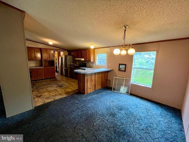 kitchen with carpet, freestanding refrigerator, a peninsula, decorative light fixtures, and under cabinet range hood
