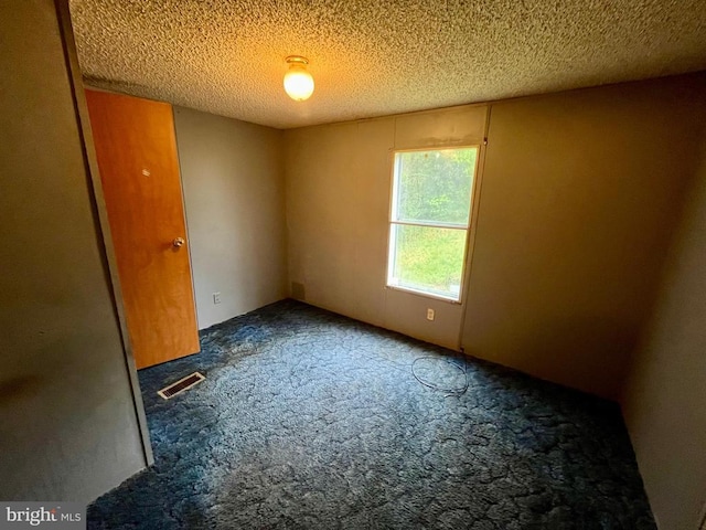 carpeted spare room with a textured ceiling and visible vents