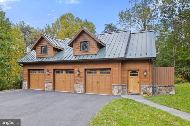 view of front of house with metal roof, stone siding, aphalt driveway, and a standing seam roof