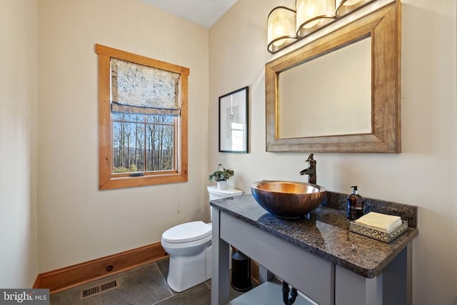 bathroom featuring visible vents, toilet, vanity, baseboards, and tile patterned floors