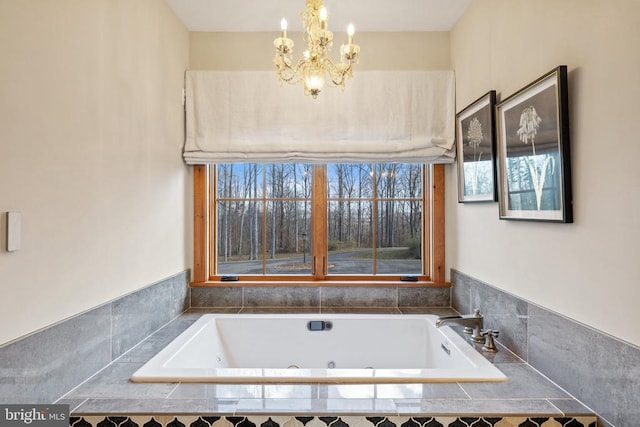 bathroom featuring a tub with jets and an inviting chandelier