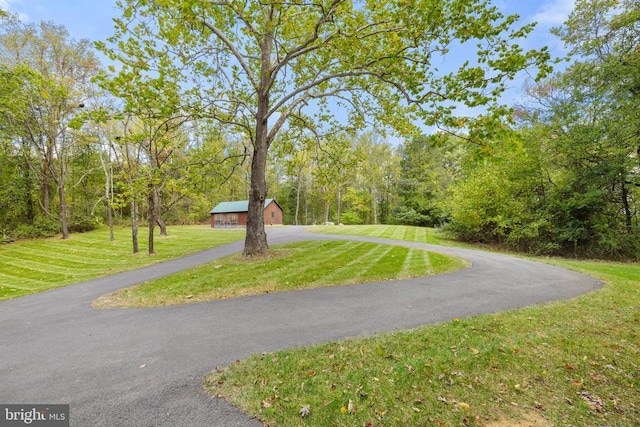 view of home's community with aphalt driveway and a lawn