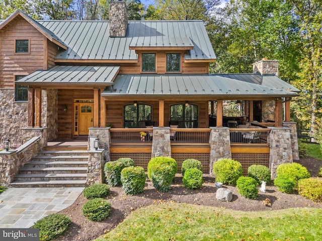 view of front of property featuring metal roof, a porch, a standing seam roof, and a chimney