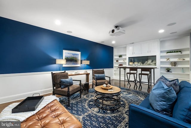 living room featuring baseboards, built in shelves, wood finished floors, and recessed lighting