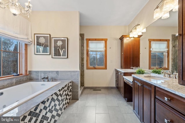 full bath with a healthy amount of sunlight, an inviting chandelier, a garden tub, and vanity