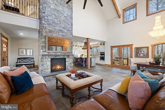 living room featuring a towering ceiling, stone finish floor, a stone fireplace, french doors, and beam ceiling