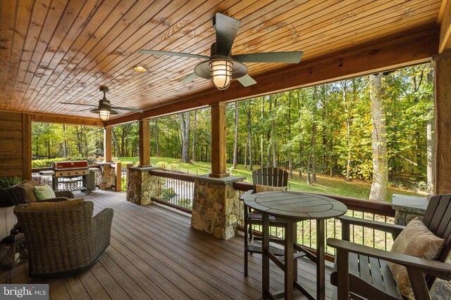 living room featuring stone tile floors, baseboards, ceiling fan, wood walls, and a fireplace