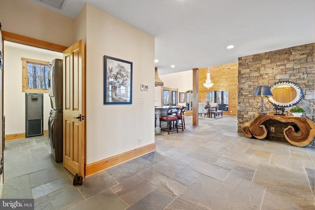 hall featuring stacked washer and dryer, recessed lighting, baseboards, and stone tile floors