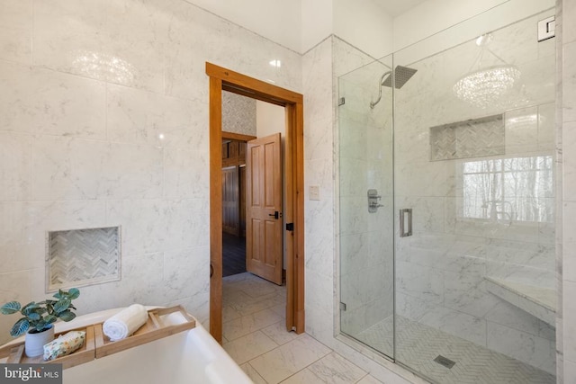 bathroom with a stall shower, marble finish floor, and tile walls