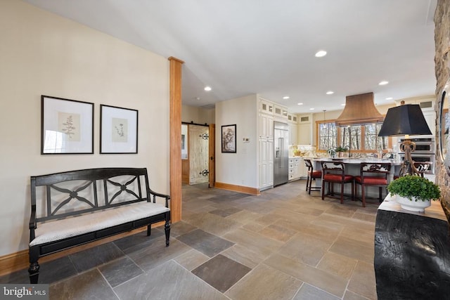 interior space with stone finish flooring, a barn door, recessed lighting, and baseboards