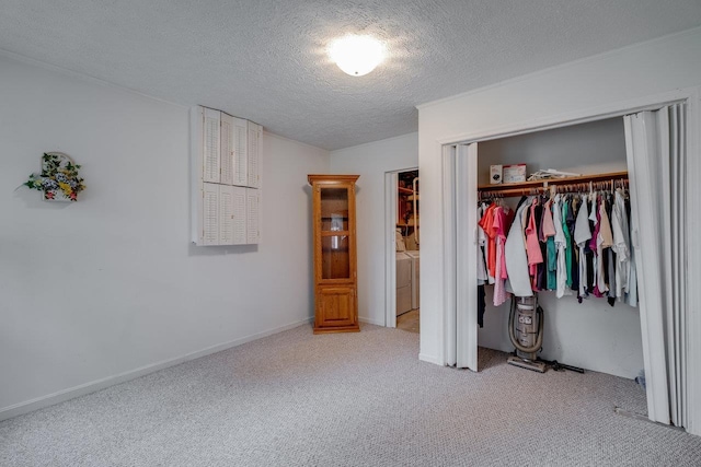 unfurnished bedroom featuring separate washer and dryer, a closet, a textured ceiling, and carpet flooring