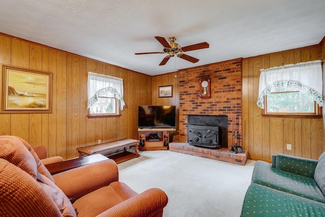 carpeted living room with ceiling fan, wooden walls, and a textured ceiling